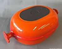 Both casseroles stacked showing exterior flame orange enamel and black base logo