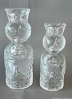 Front view of both clear glass figural candle holders