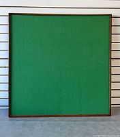 Front view of green felt puzzle board in wooden frame