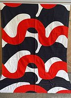 Full view of fabric panel hanging, showing entire abstract red/white/black pattern