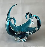 Front view of teal blue freeform art glass bowl with clear base and three curled arms