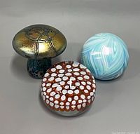 Front view of three paperweights showing overall forms and finishes