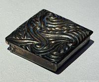 Closed trinket box angled view showing repousse design and tarnished patina