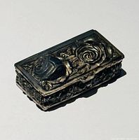 Closed pill box showing raised rose motif on lid