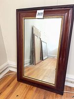 Full view of framed mirror leaning against wall