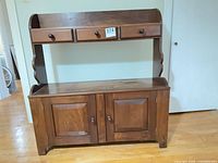 Front view showing three drawers, open surface, and two-door cabinet