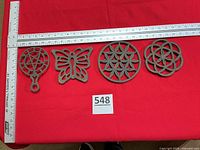 All four cast iron trivets lined up with rulers for scale