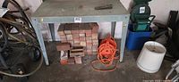 Front view of galvanized workbench showing bricks underneath (not included) and orange cord (not included)