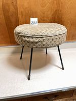 overall view of round hassock footstool on four metal legs