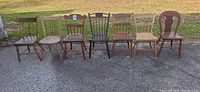 All seven mismatched wooden chairs lined up outdoors