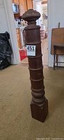 Full view of turned wood newel post with square base and rounded cap