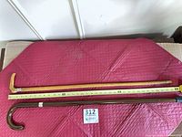 Both canes laid flat with measuring tape showing length