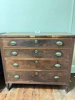 Front view of four-drawer wood dresser with metal pulls and keyholes