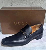 Left side view of right shoe in front of Gucci box
