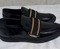 Side view of both loafers showing leather finish, strap, and sole