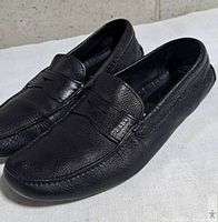 Three-quarter view of both loafers showing leather texture and logo