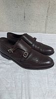 Left side view of the pair of brown leather double monk strap wingtip shoes