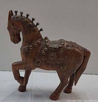 Left side view of carved wooden horse with brass studs