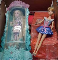 Turquoise ice-themed case with blond doll, orange fridge accessory, and blue-skirt Barbie doll in box