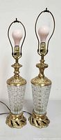 Two brass and cut glass table lamps with bulbs installed, cords visible