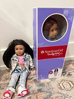 Boxed doll standing upright next to loose doll seated