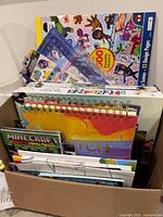 Boxed assortment of art pads, coloring books, sticker packs, Minecraft magnetic puzzle visible