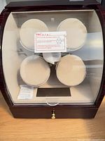 Front view of watch winder showing four winding heads behind clear window and drawer below