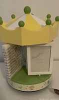 Carousel photo album showing yellow crown roof, green base, photo frame panels