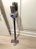Full view of Dyson V6 stick vacuum on wall dock
