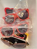 Stack of red heart-shaped and other sunglasses, some sealed in plastic
