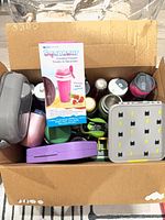 Box containing assorted water bottles, tumblers, lunch boxes, and Squeezur cup packaging