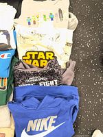 Stack of folded graphic shirts including Minecraft, Star Wars, grey patterned shirt, blue Nike