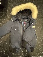 Moose Knuckles navy bomber jacket front view showing hood trim and logo