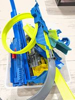 bin containing assorted blue track, yellow loop pieces and grey ramp