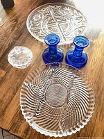 Group shot showing both clear trays, covered dish with lid, and pair of blue candlesticks