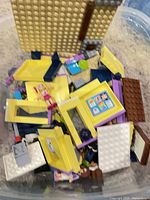 Tub of loose yellow and blue Lego bricks with minidoll visible