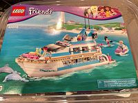 Box lid or manual image showing LEGO Friends Dolphin Cruiser 41015 artwork