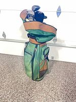 Full view of green and brown Spalding golf bag with cover and clubs visible