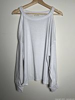Front view of white cold-shoulder long-sleeve shirt on hanger