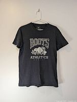 Front view of dark gray Roots Athletics t-shirt showing graphic