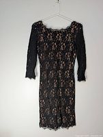Full front view of black lace dress on hanger