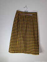 Full view of yellow and black plaid wrap skirt on hanger