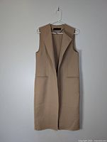 Front view of beige Zara sleeveless long vest showcasing open front and pockets