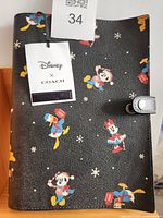 Front view of notebook cover showing Disney X Coach tag and character pattern