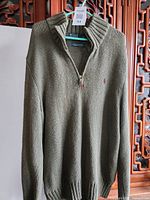 Front view of olive green quarter-zip sweater on hanger showing overall condition