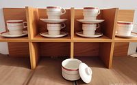 Full set of six cup-and-saucer pairs on shelf with sugar bowl in foreground
