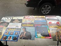 Front view showing two rows of various LP sleeves on table, highlights Rocky, Chart Hits, Santa Esmeralda, Eddie Murphy, Time Exposure