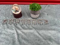 All three items laid out: snow globe, planter with faux plant, metal scarf hanger