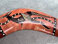 Front of boomerang showing painted Aboriginal-style motif and artist signature Julie A