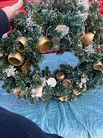 Front view of full wreath showing evergreen branches and gold pods